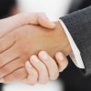 Close-up of the hands of two businesswomen shaking hands with two businessmen in background --- Image by © Royalty-Free/Corbis